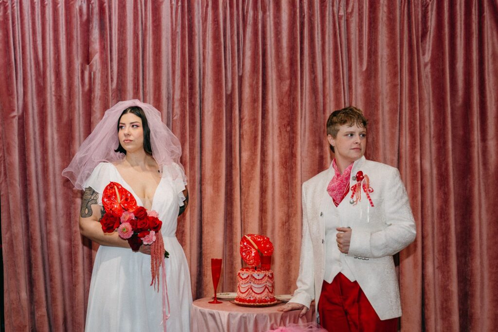LGBTQ couple dressed in vintage-inspired elopement attire posing inside The Pink Lantern cocktail bar in Birmingham Alabama.