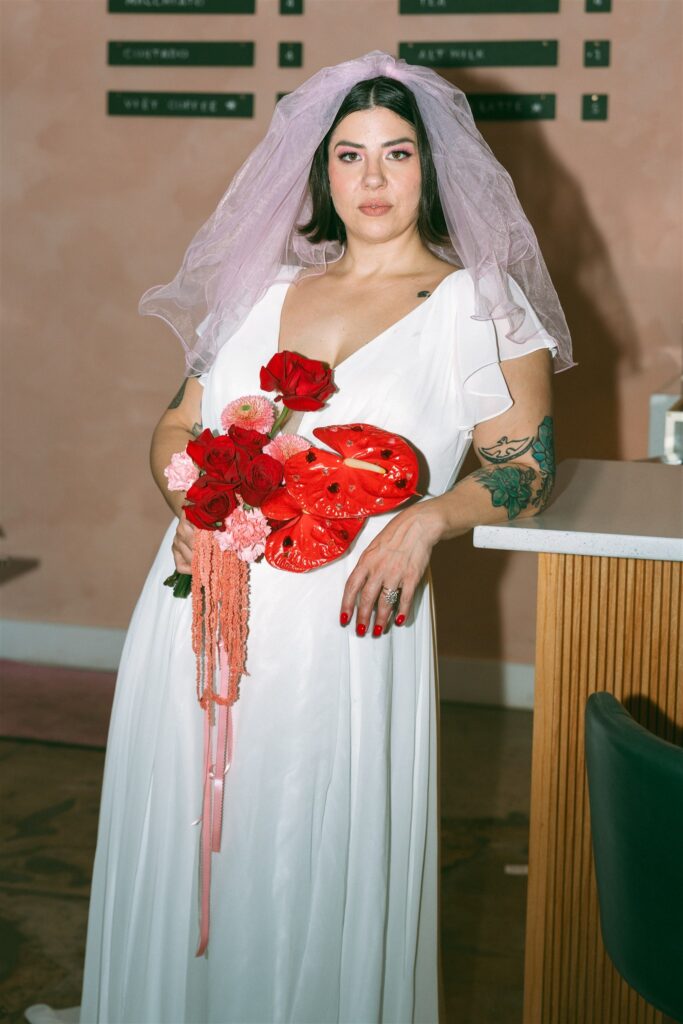 A bride leans against a counter at The Pink Lantern Birmingham for her Alabama elopement 