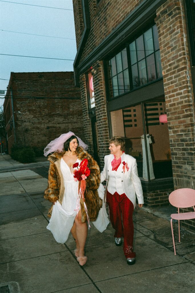 LGBTQ couple dressed in vintage-inspired elopement attire posing inside The Pink Lantern cocktail bar in Birmingham Alabama.