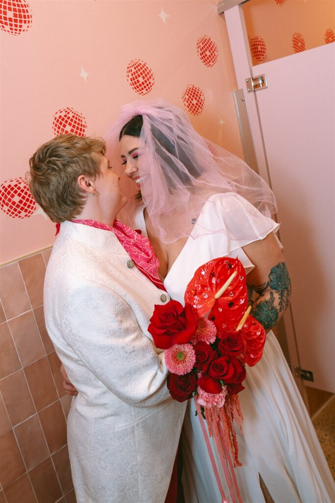 LGBTQ couple dressed in vintage-inspired elopement attire posing inside The Pink Lantern cocktail bar in Birmingham for their Alabama elopement
