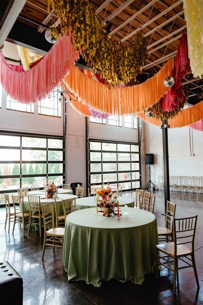 The Sage Birmingham reception tables with colorful florals, citrus details, and orange taper candles