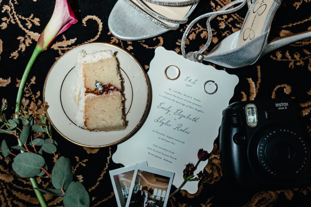 A wedding flat lay including florals, cake, rings, instax photos, and invitations is displayed at The Florentine, a Birmingham wedding venue