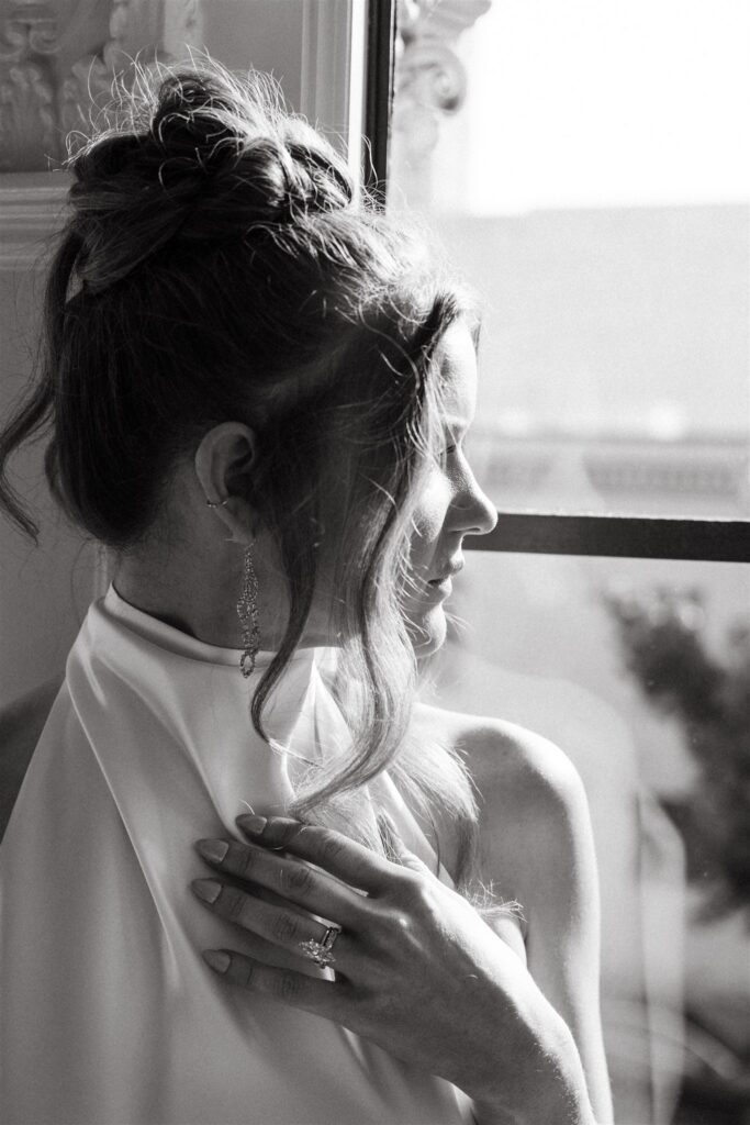 A black and white bridal portrait showcases a bride looking out the window of the upper floor at The Florentine Birmingham 