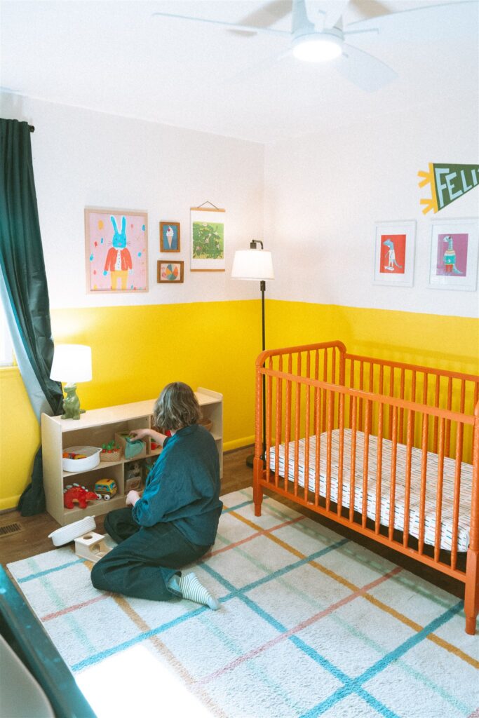 A mother tidies her son's shelf in his nursery during a photoshoot in their home with an alabama family photographer