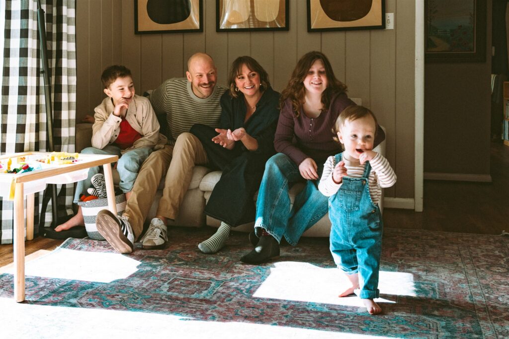 A family of five smile in their family room during an in-home session with family photographer birmingham al