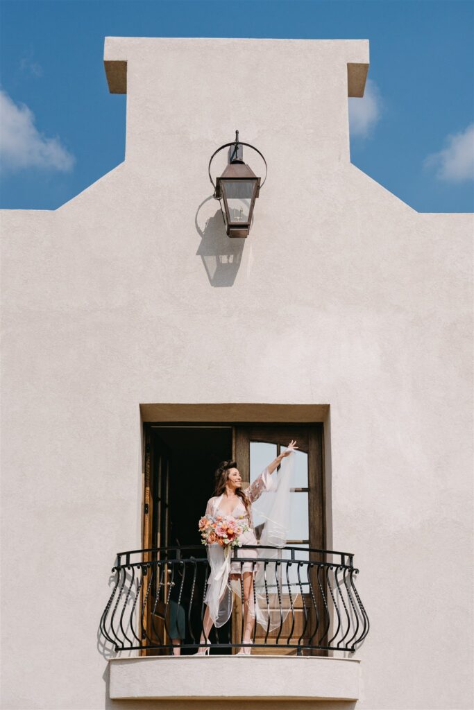A bride poses for a portrait off the balcony at her Stonehaven wedding 