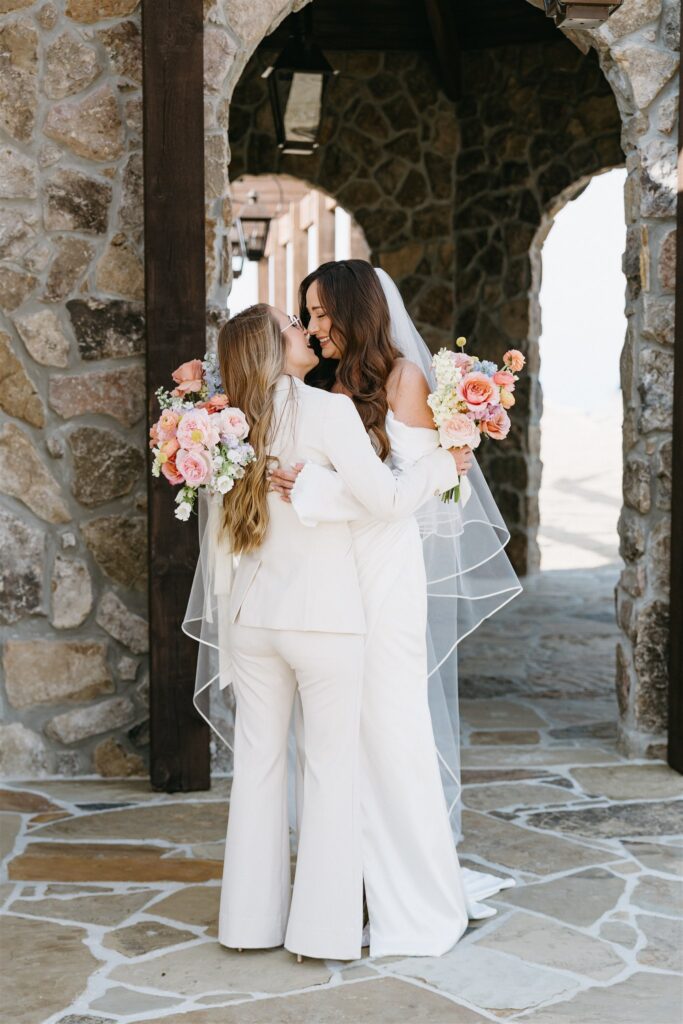 Brides pose for a portrait under the stone arches at their Stonehaven wedding 