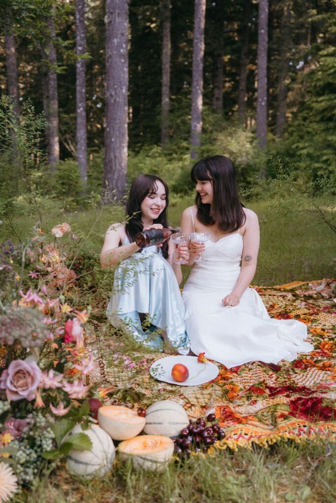 Two brides enjoy a picnic surrounded by florals at their Portland Oregon elopement