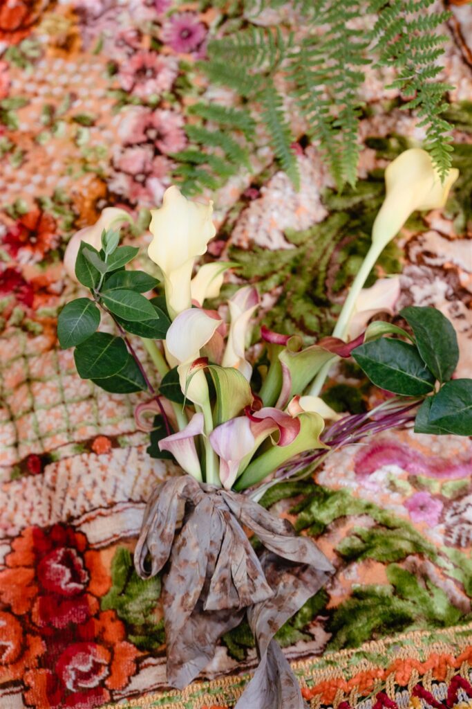 An up close shot depicts a colorful bridal bouquet set atop a throw rug by Wildflower Portland for a Portland Oregon Elopement
