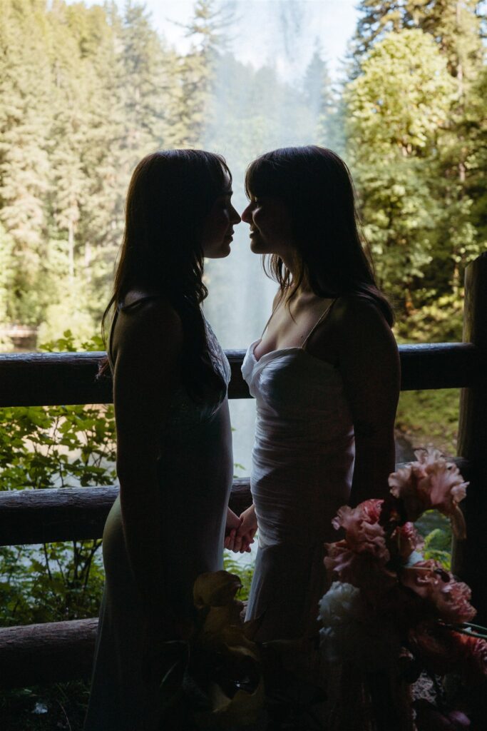 The silhouette of two brides leaning in for a kiss at their Oregon elopement