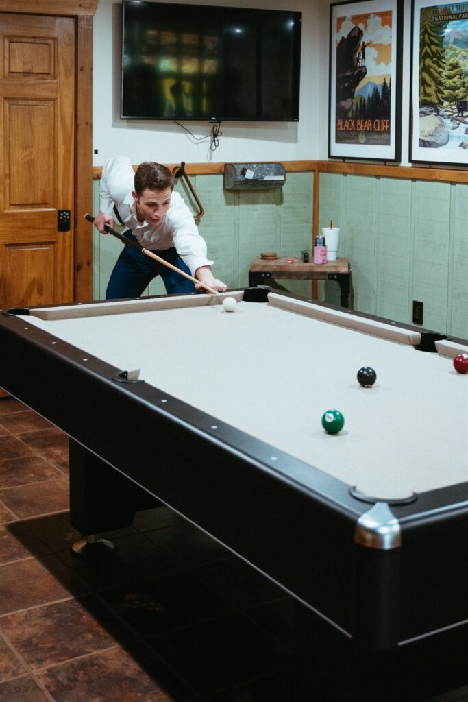 A groom plays pool in the basement of a Smoky Mountains cabin before his Pigeon Forge elopement. 