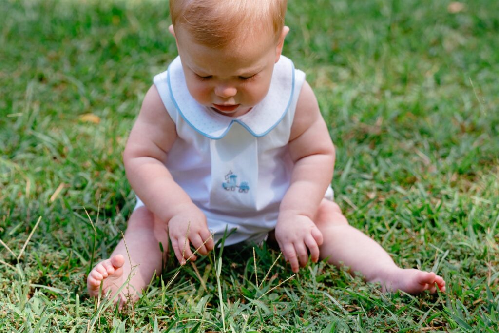 A baby plays in the grass at an  Alabama park in a photo taken during family portraits birmingham.