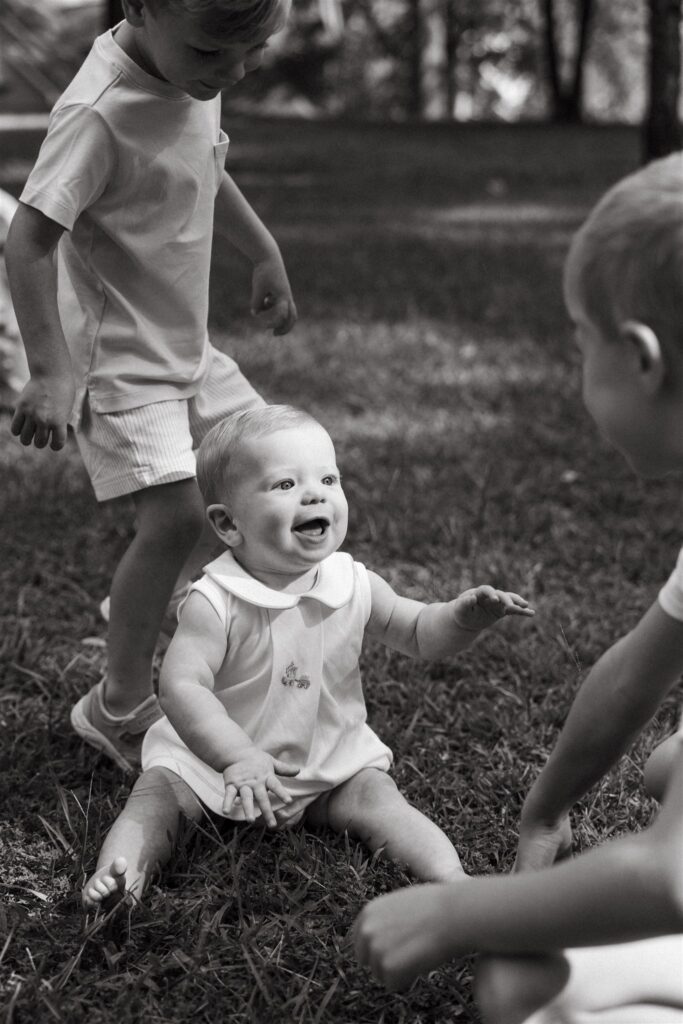 Two older brothers interact with their younger sibling at a local park during family photography Birmingham. 