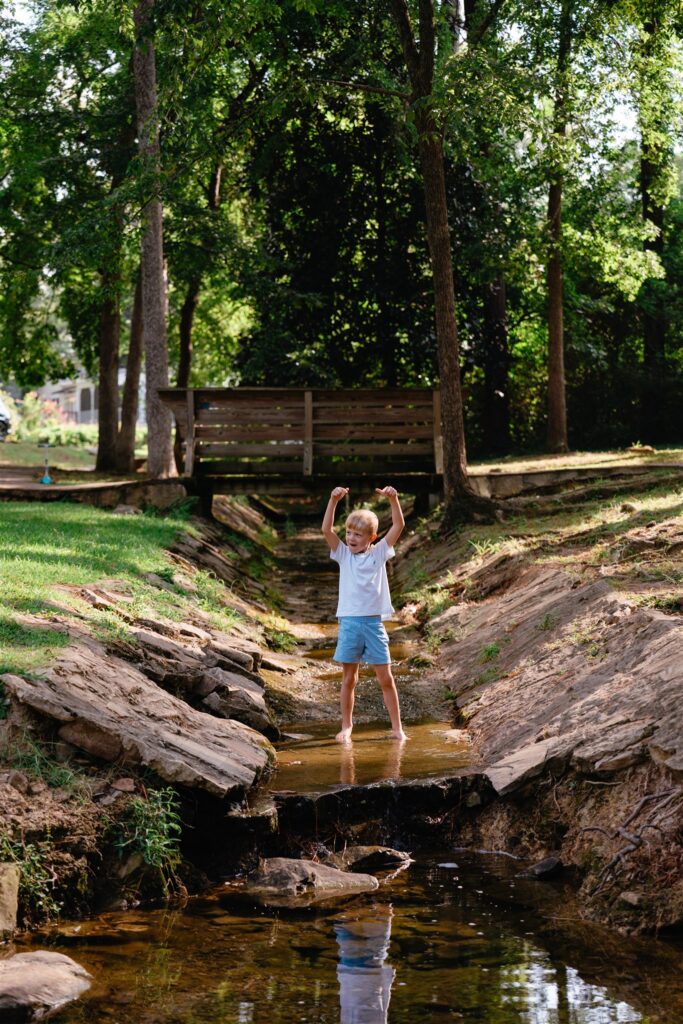 A boy explores a creek at an Alabama park taken during family photography birmingham. 