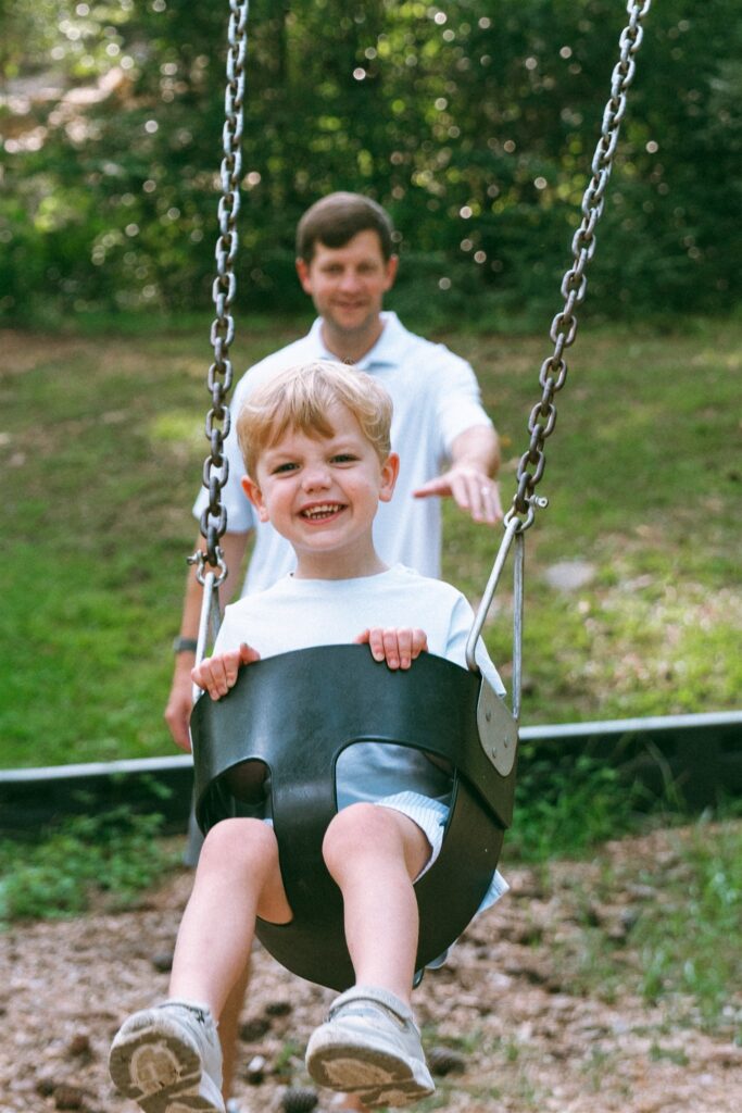 A father pushes his son on a swing during family portraits birmingham.