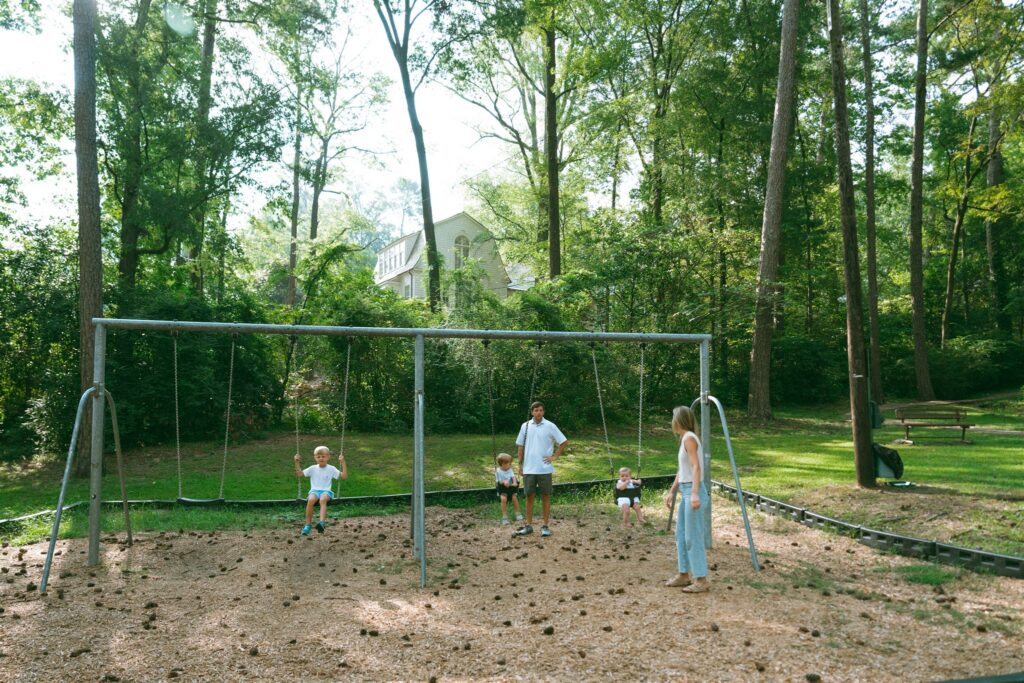 A family of 5 is photographed swinging at a local park during family photos Birmingham Alabama. 