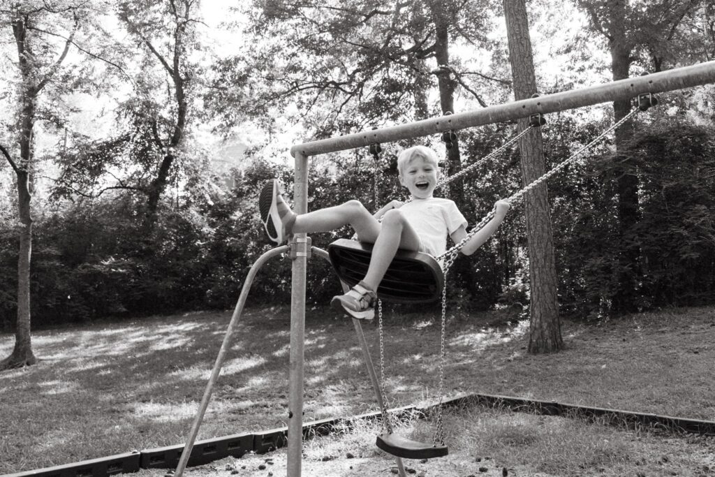 A young boy smiles as he swings on a playset at a local park during family photos in Birmingham, AL. 