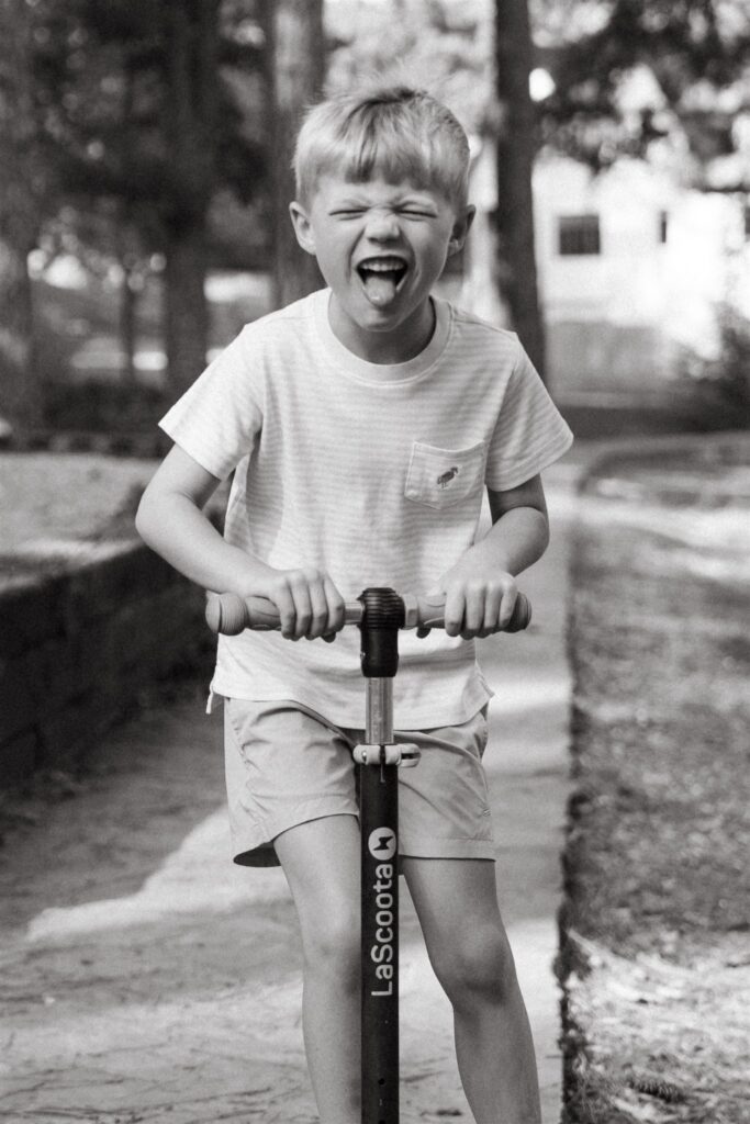 Candid family portraits birmingham show a young boy riding his scooter. 