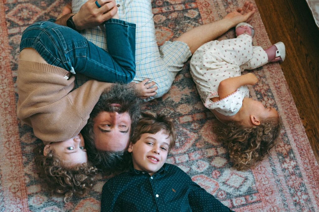 A father lies on the floor of his home with his three children during lifestyle family portraits Birmingham Alabama. 