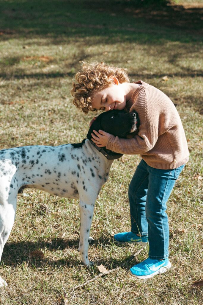 A young boy hugs his dog in his backyard during  lifestyle family portraits Birmingham Alabama.