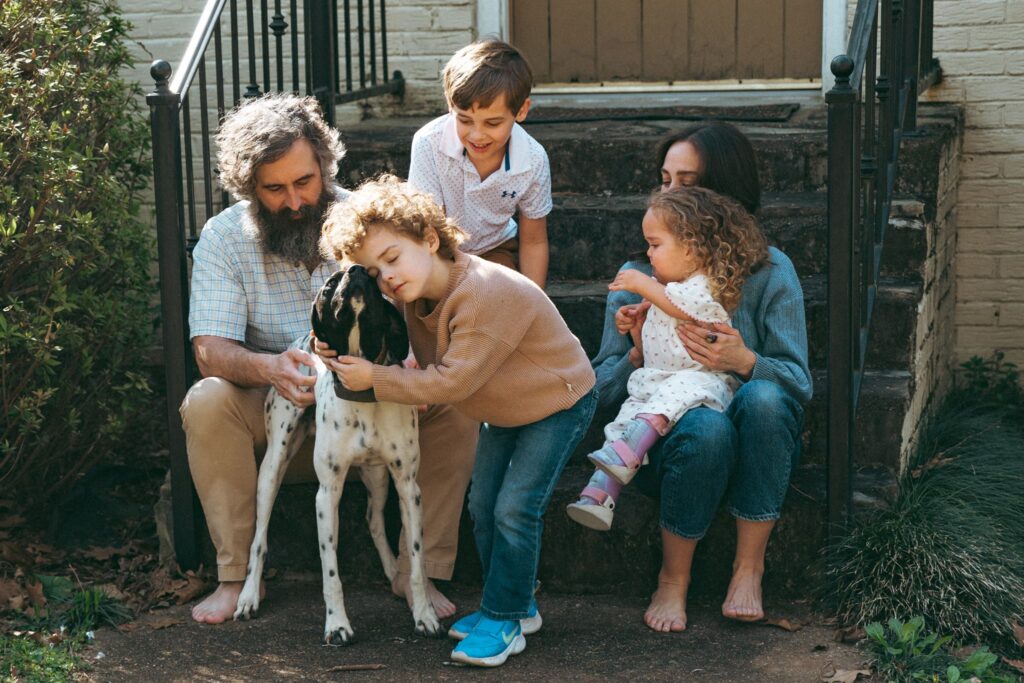 In home family portraits in Birmingham feature a family of 5 with their family dog on the front porch of their Alabama home.