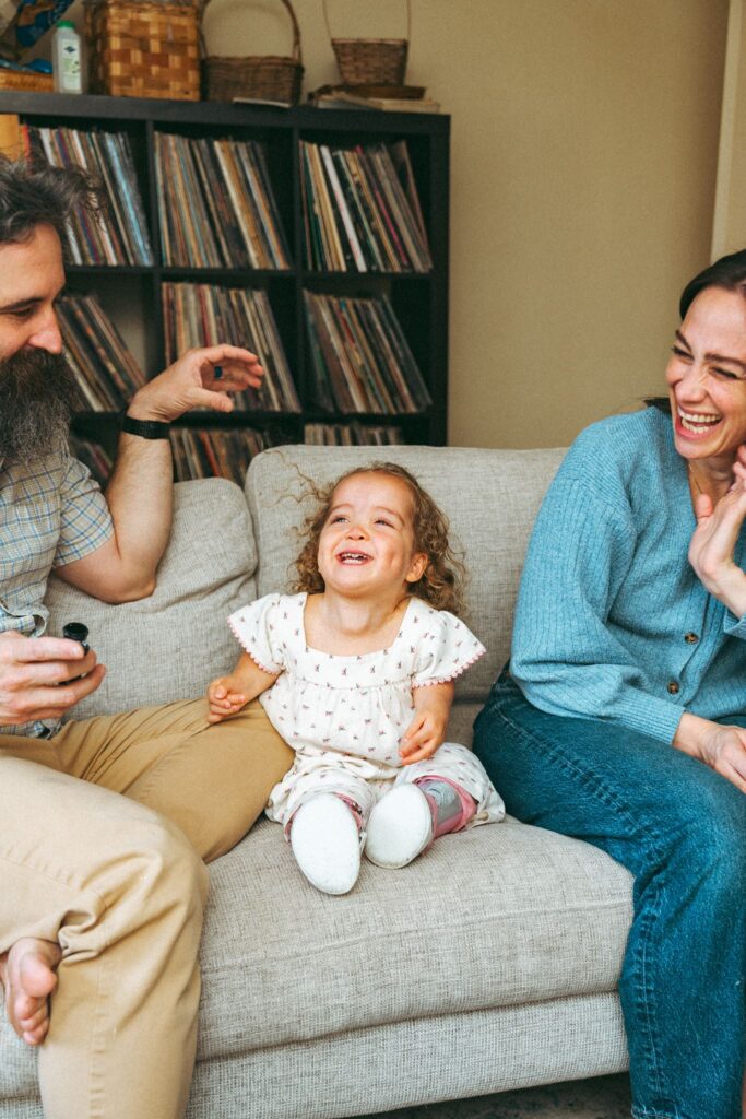 A father plays with his daughter as his wife laughs during lifestyle family portraits in Birmingham AL.