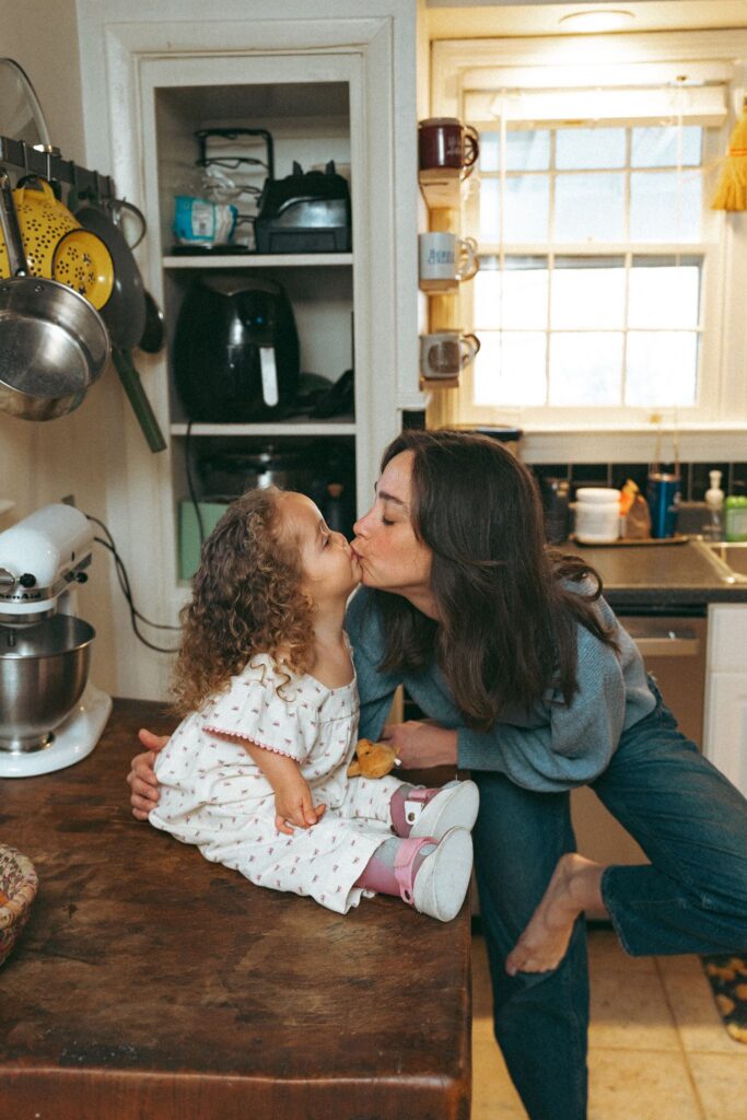 A mother kisses her toddler in the kitchen of her Alabama home during an in home family photoshoot Birmingham. 