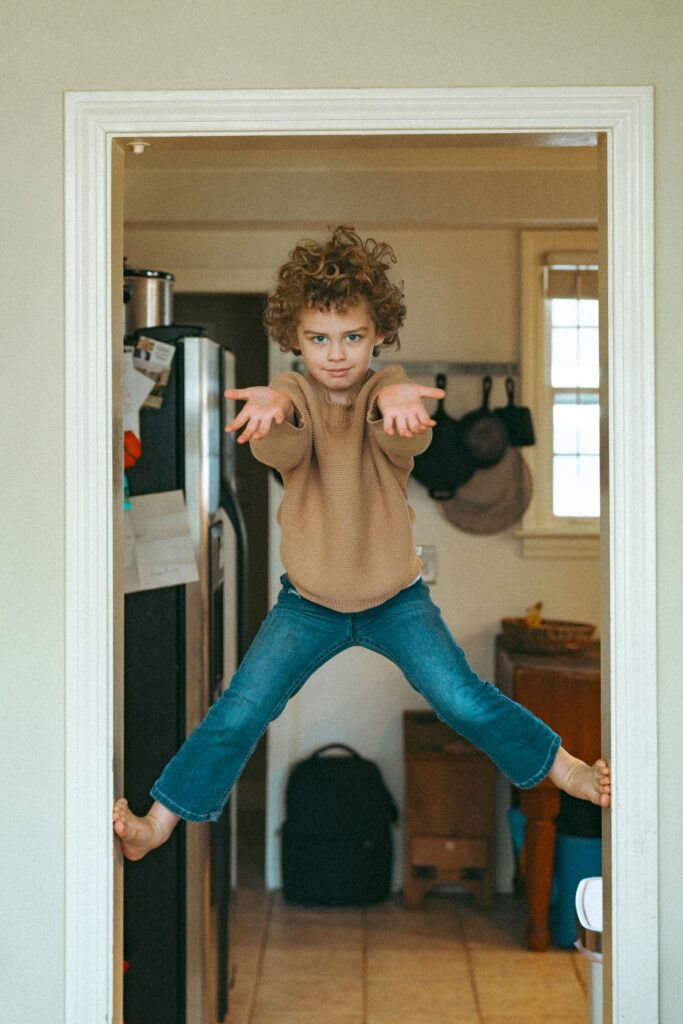 A young boy climbs the doorway of his Alabama home during a lifestyle shoot with a family portrait photographer Alabama. 